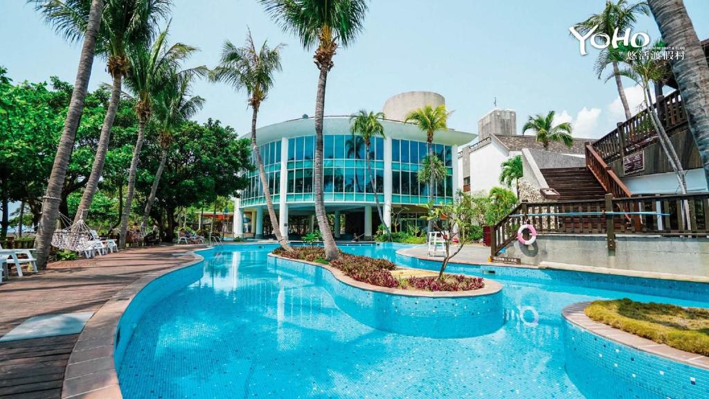 a resort with a swimming pool and palm trees at Yoho Beach Resort Kenting in Hengchun