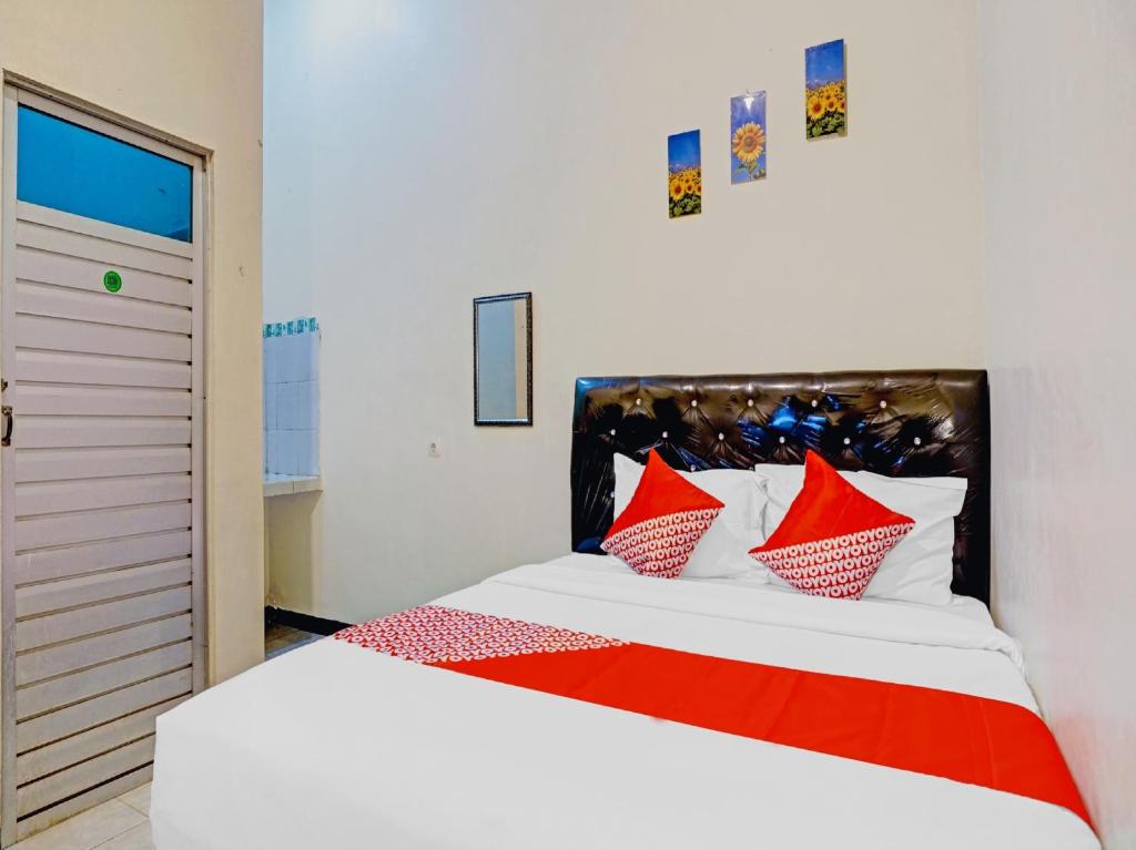 a bedroom with a bed with red and white pillows at OYO 2835 Sakinah Family Residence in Tulungagung