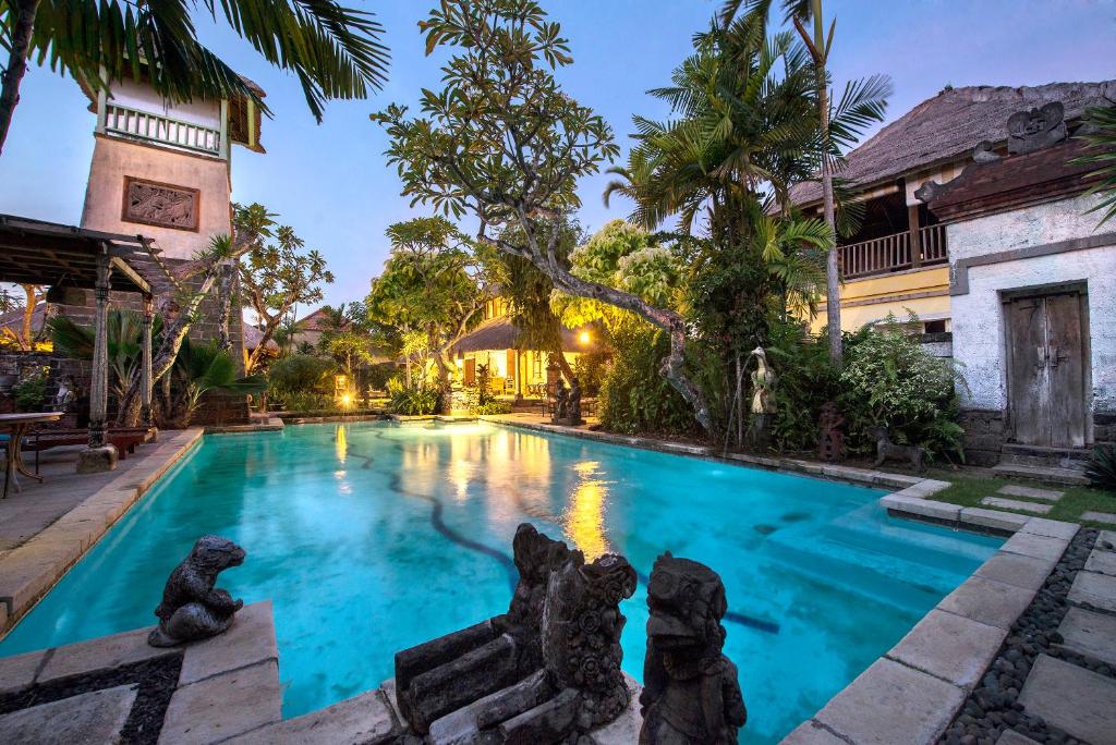 a swimming pool in front of a house at Bebek Cottages Sanur in Sanur