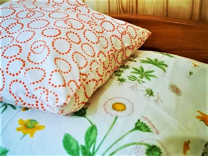 a bed with a white pillow and a floral sheet at Penzión Pod orechom in Turčianske Teplice