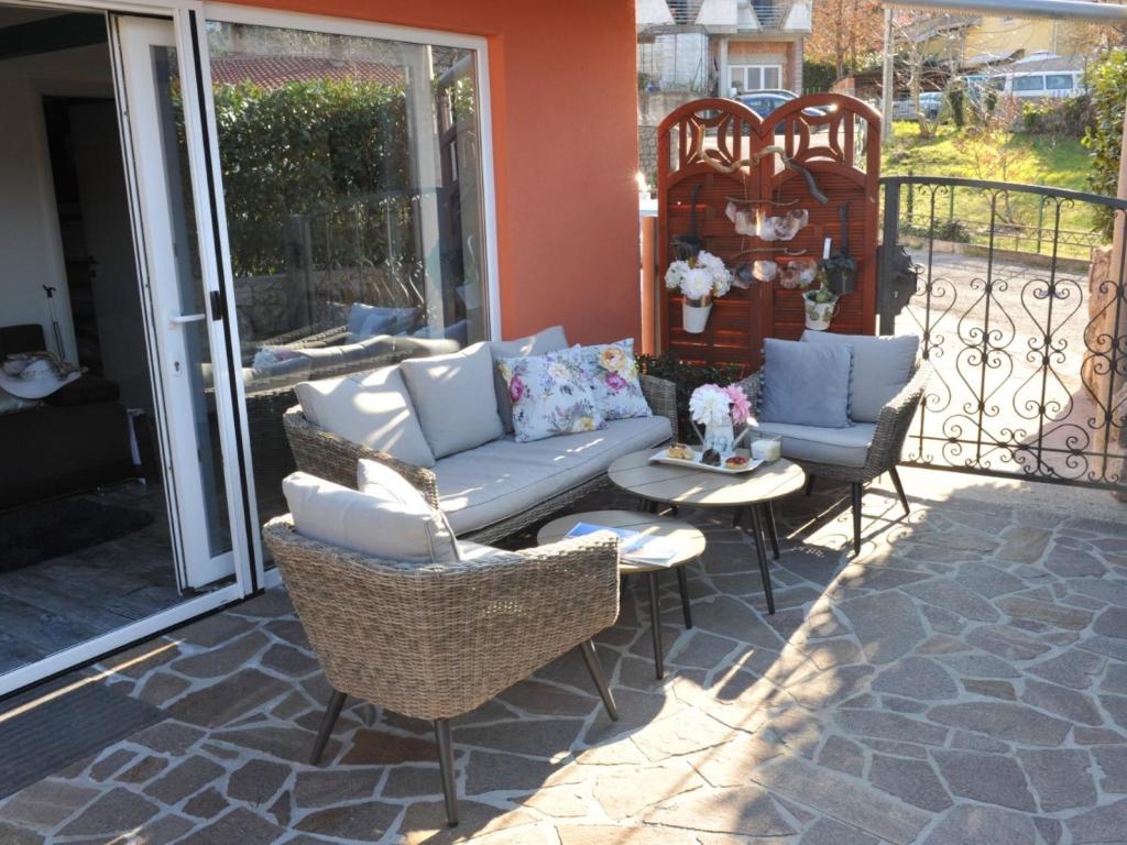 une terrasse couverte avec un canapé et des chaises. dans l'établissement Shanti Home, à Lovran