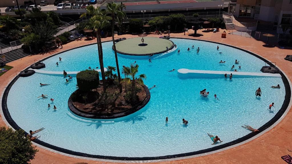 una vista sull'alto di una grande piscina con persone di Ideal familias en urbanización de lujo a 600m de la playa Levante con Wifi, AC y Parking a Benidorm