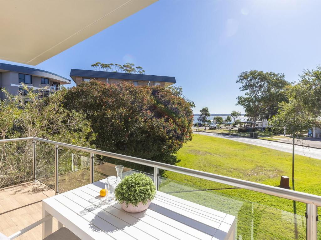 a white table on a balcony with a view of a field at Villa Ellisa 4 beautiful unit with beautiful water views at Little Beach in Nelson Bay