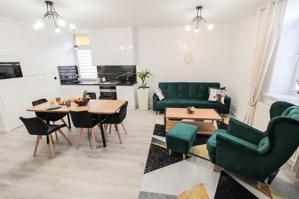 クリニツァ・ズドルイにあるApartament Złoty Jeleń - garaż gratisのリビングルーム(緑の家具、テーブル、椅子付)