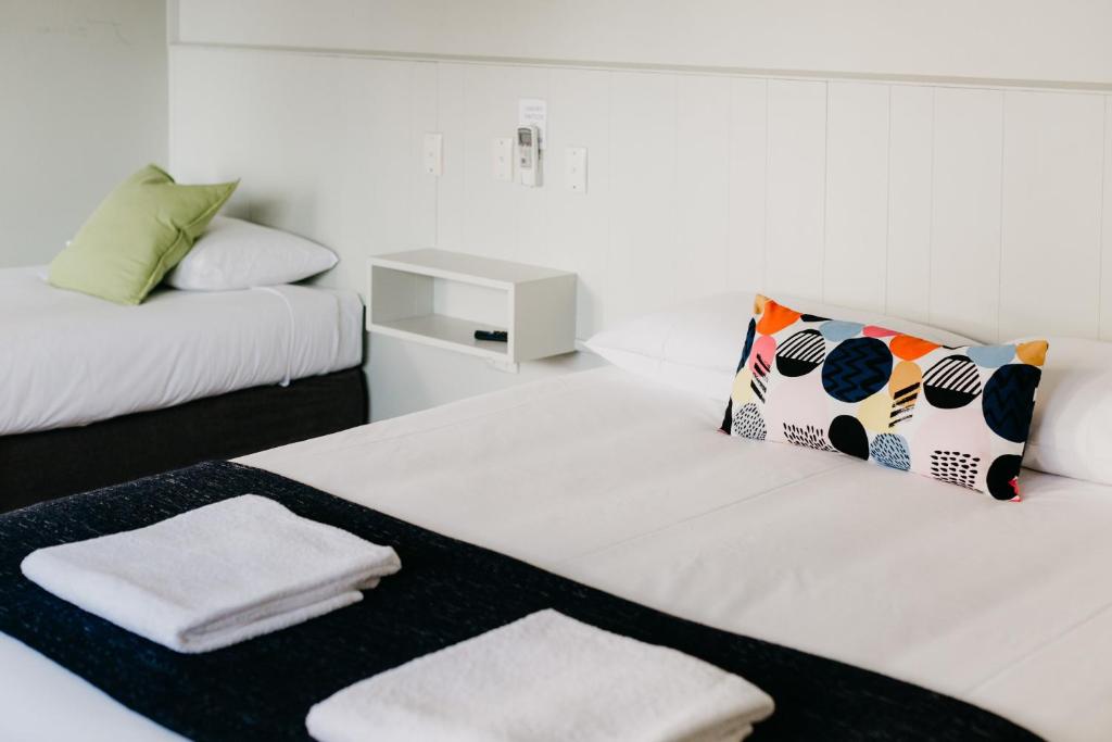 um quarto branco com duas camas com toalhas em Finley Country Club Hotel Motel em Finley