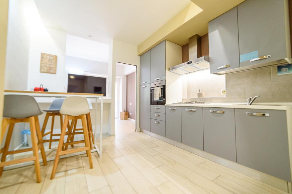 cocina con armarios grises y barra con taburetes en Ostia Holiday Al 138, en Lido di Ostia