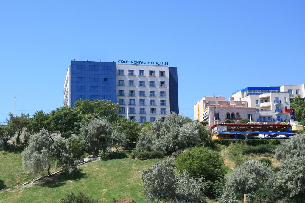 a tall building in the middle of a city with trees at Continental Forum Constanta in Constanţa