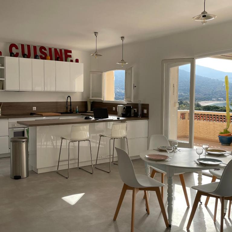a kitchen with white cabinets and a table and chairs at Villa Turquoise Sagone in Sagone