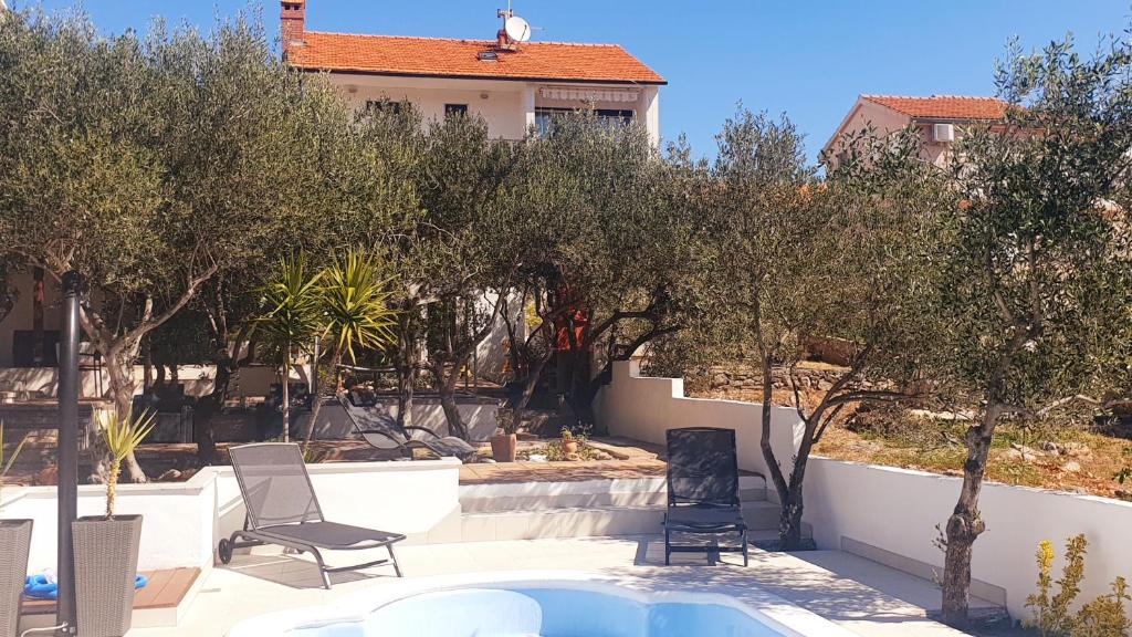 een achtertuin met een zwembad en bomen en een huis bij Compelx with detached house and spacious apartment in Stari Grad