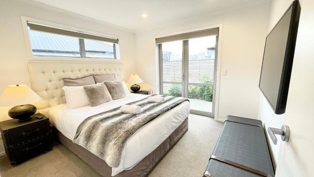 a bedroom with a large bed and a flat screen tv at Modern Living in Queenstown