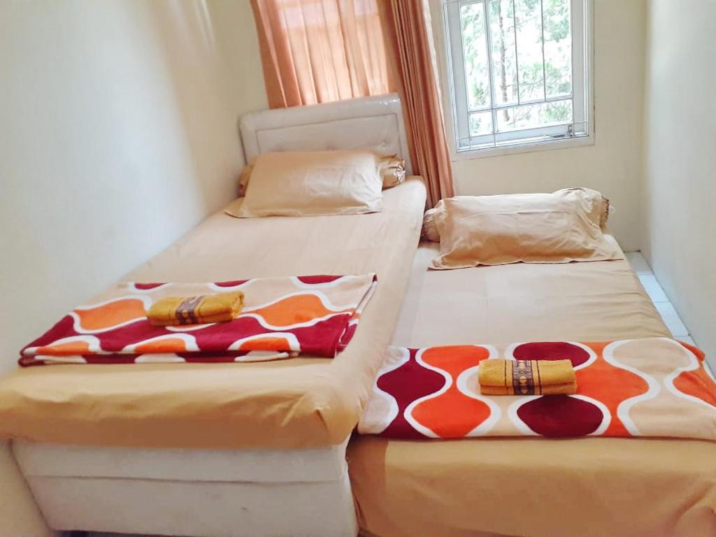 two beds sitting next to each other in a room at Kost Carmelia Syariah Baranangsiang Bogor in Bogor