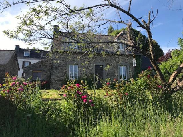 una vieja casa de piedra con flores delante en Les Chambres De Napoleon en Lannédern