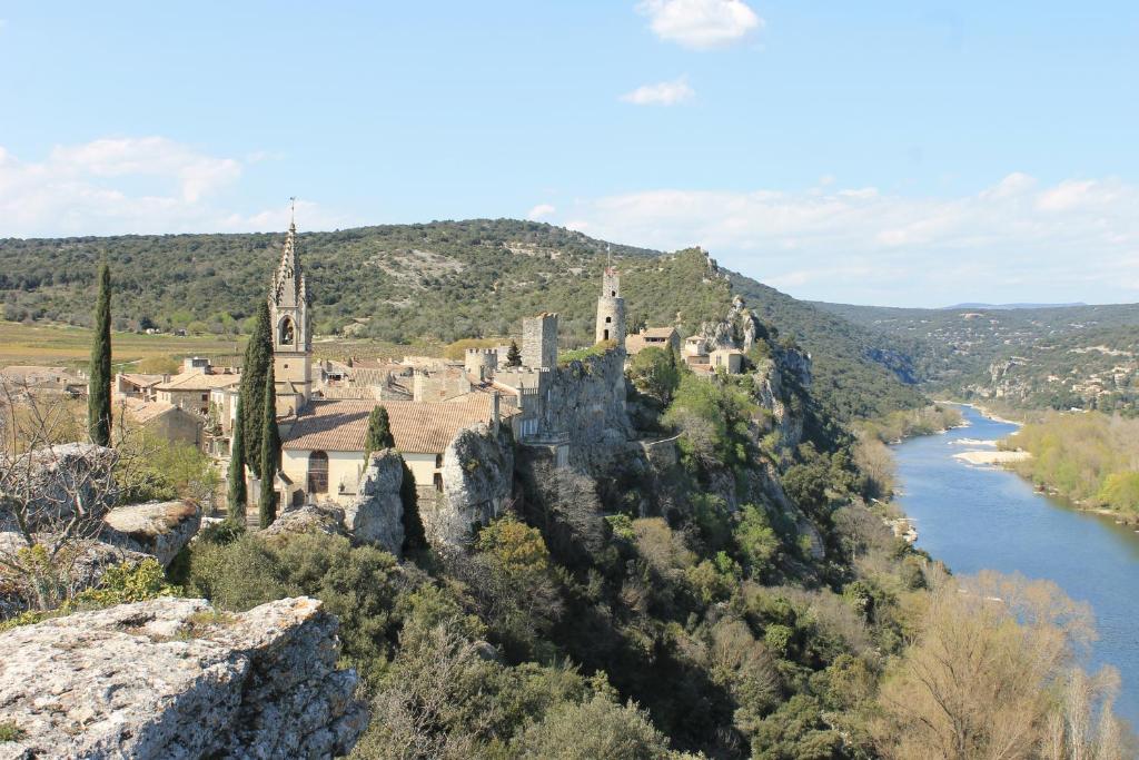a castle on a hill next to a river at Le cabinet de curiosités in Aiguèze