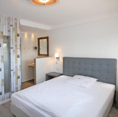 a bedroom with a large white bed and a mirror at Hotel Haus Berger in Cologne