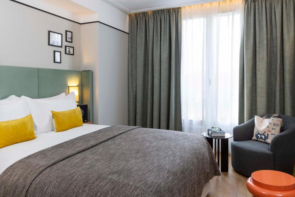 une chambre d'hôtel avec un lit et une chaise dans l'établissement Hotel Le 37 Bis, à Neuilly-sur-Seine