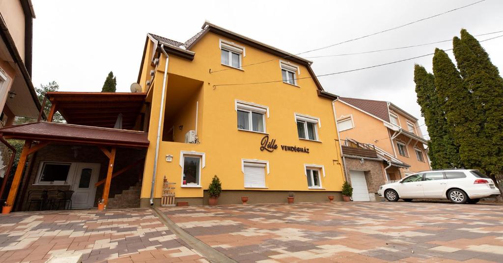 żółty dom z samochodem zaparkowanym przed nim w obiekcie Lilla Vendégház w Miskolc-Tapolca