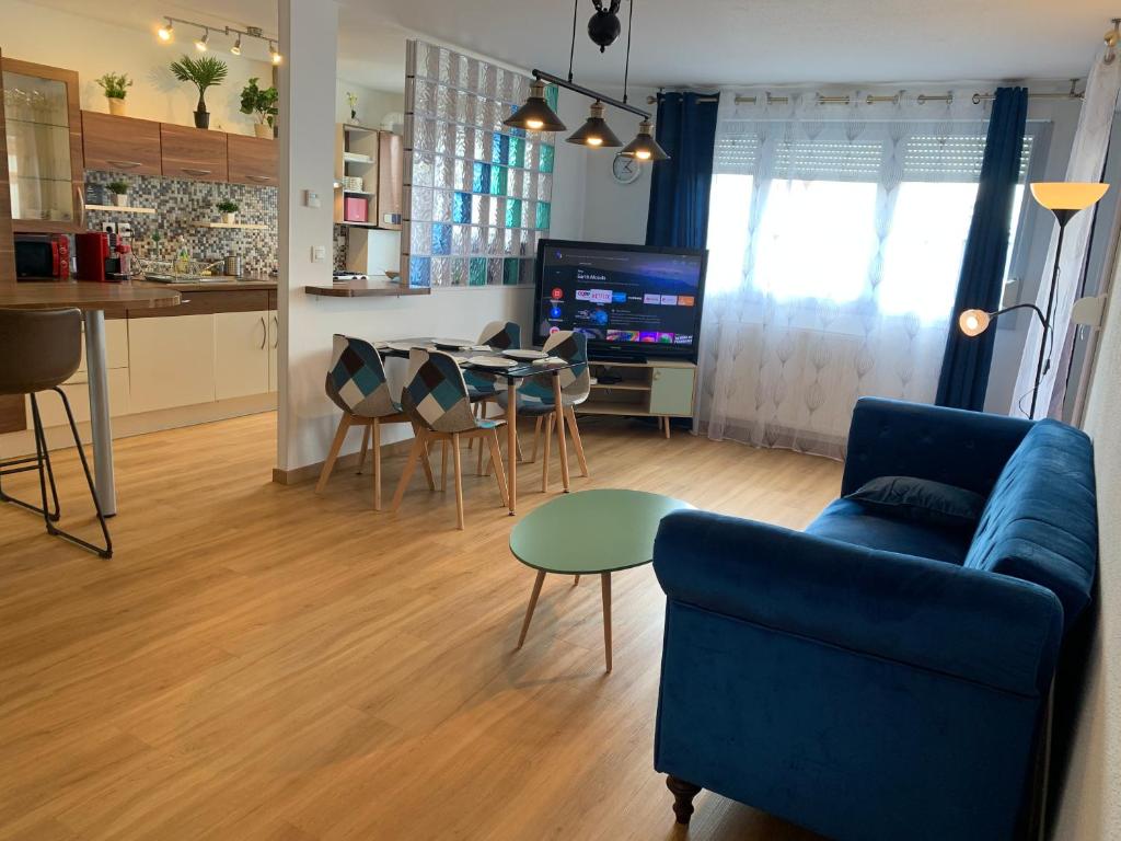 un salon avec un canapé bleu et une table dans l'établissement Sion City Mulhouse centre - parking et balcon-wifi 5G gratuit, à Mulhouse