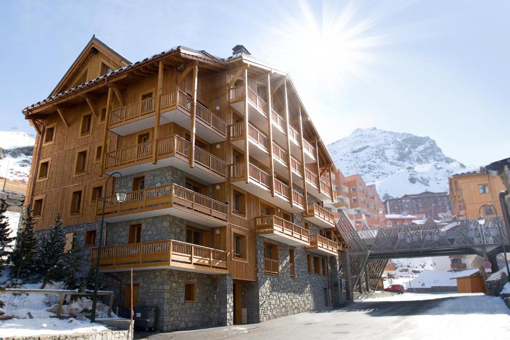 um grande edifício de madeira com uma montanha ao fundo em Le Sabot de Vénus em Val Thorens