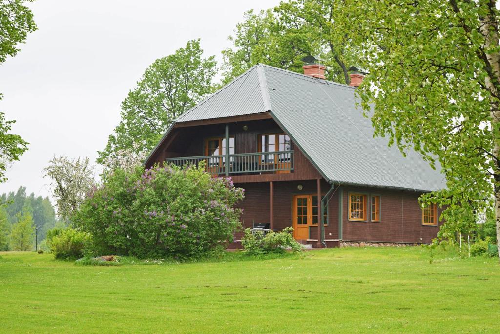 a brown house with a metal roof on a green field at Brivdienu maja Ūtkas in Bauņi