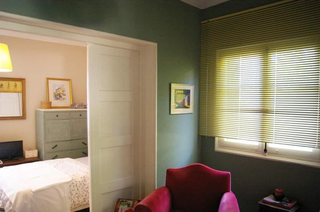 a bedroom with a bed and a window with a red chair at Garden House in Corfu in Corfu Town