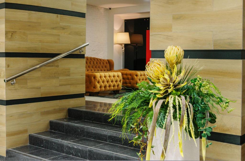 a lobby with a staircase with a couch and flowers at Salut Hotel in Balakovo