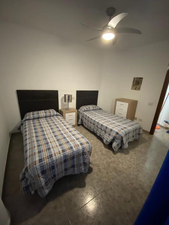 a bedroom with two beds and a ceiling fan at Apart Juan de Cardona in Arinaga