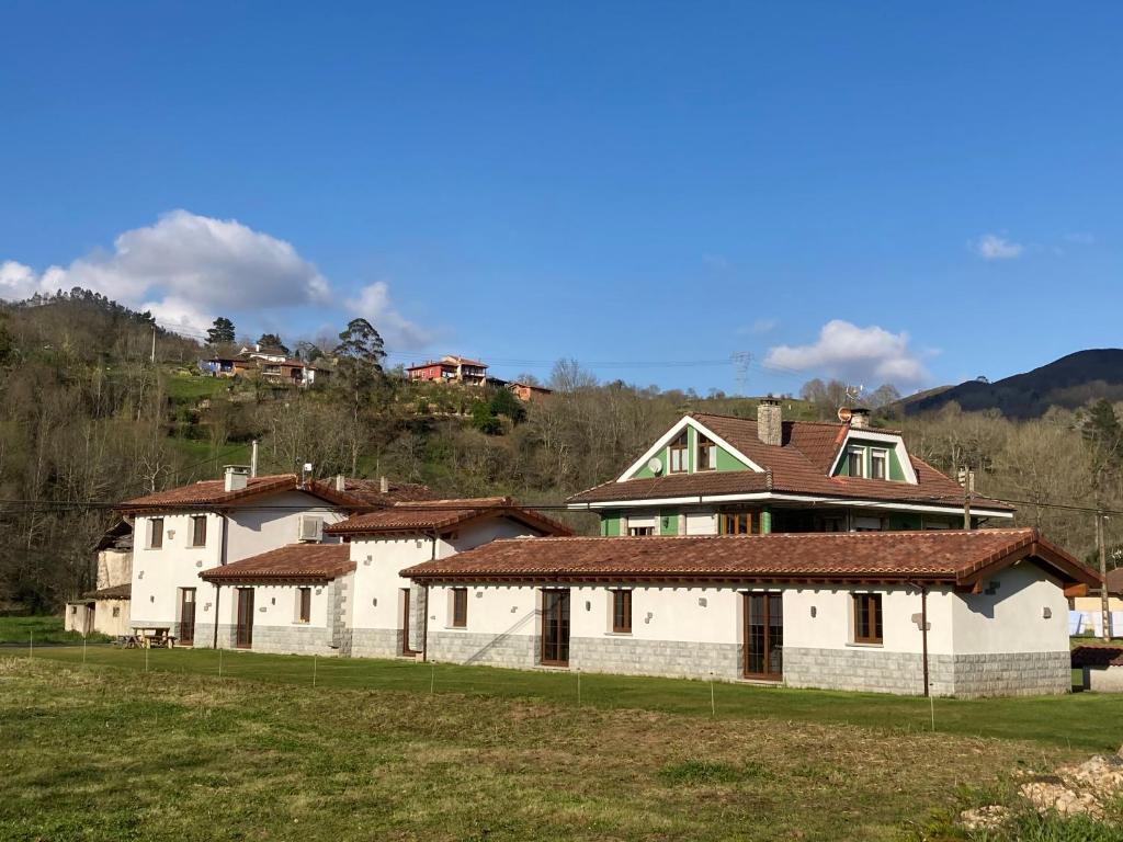duży biały dom z brązowymi dachami na polu w obiekcie Apartamentos La Presa El Molin w mieście Cangas de Onís