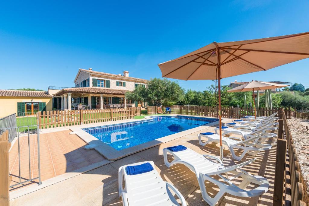a swimming pool with lounge chairs and an umbrella at Finca Can Valero in La Aranjasa