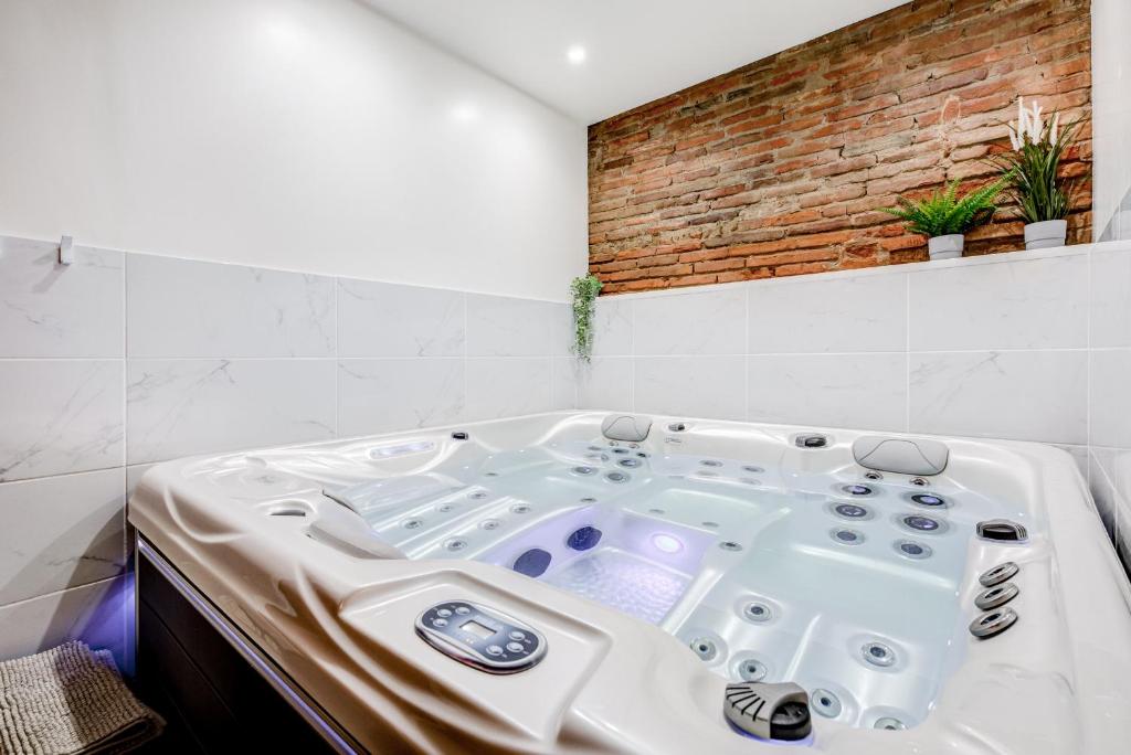 a white bath tub in a room with a brick wall at Spa des Carmes in Toulouse