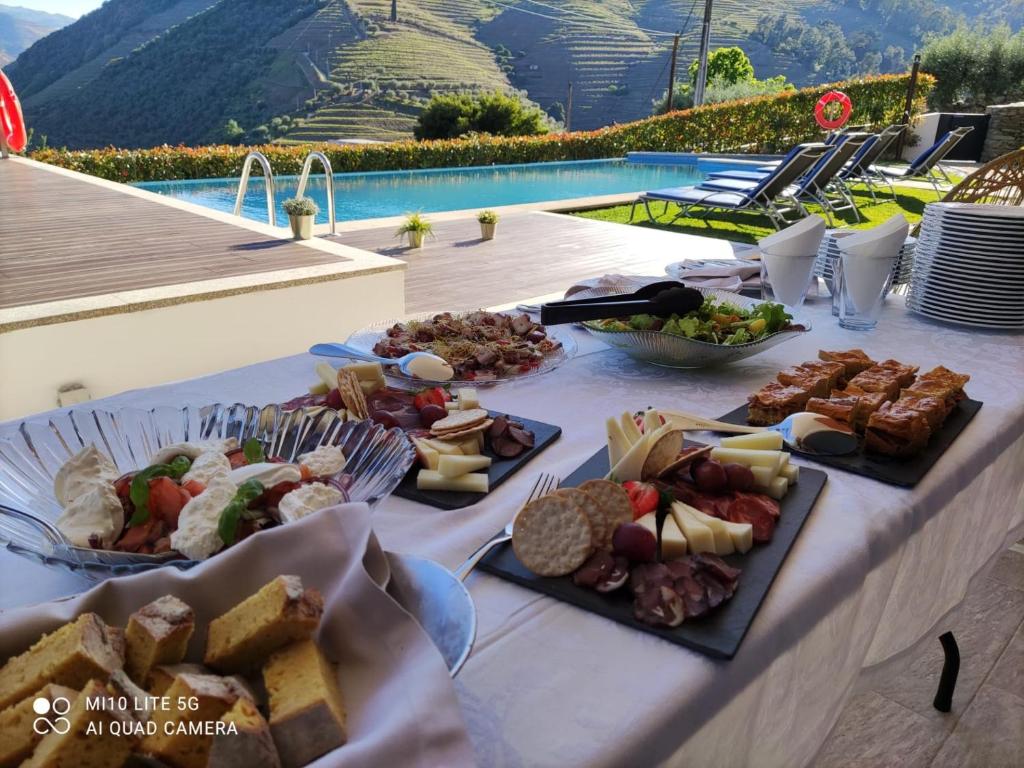 a table topped with plates of food next to a pool at Casa D'Os Reais in São Cristóvão do Douro