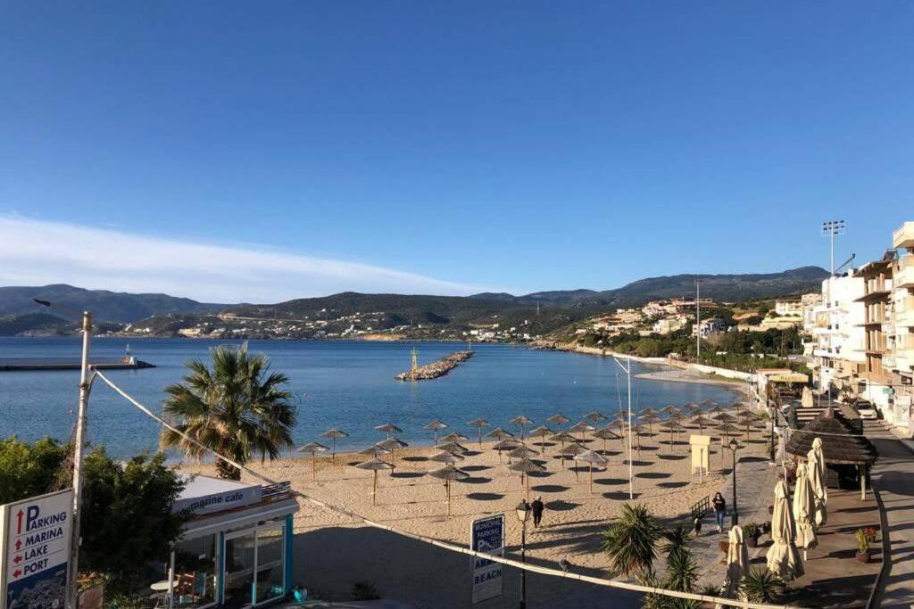 einen Strand mit Liegestühlen und Sonnenschirmen am Strand in der Unterkunft Sea Front in Agios Nikolaos