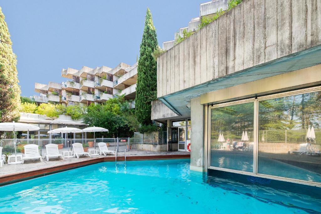 a swimming pool in front of a building at SOWELL Family Le Vallon in Grospierres