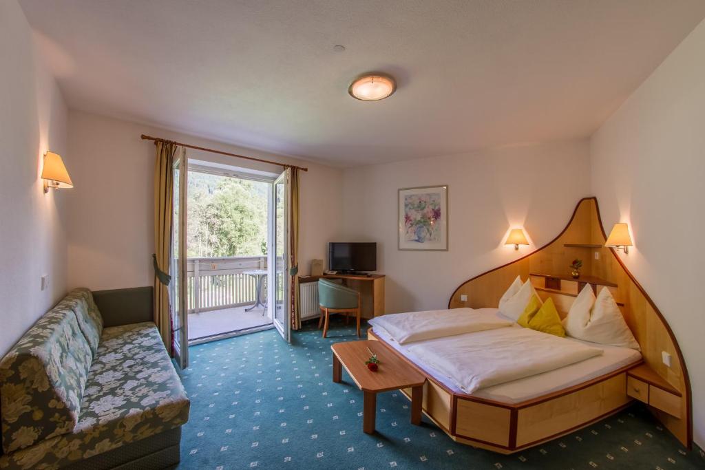 a hotel room with a bed and a couch at Appartement Hotel Erlhof Deluxe in Lutago