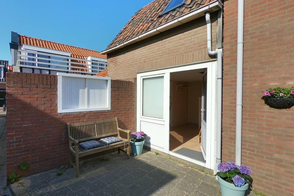 un banc installé à côté d'un bâtiment en briques dans l'établissement Zomerhuis At Sea op top locatie in Egmond aan zee, à Egmond aan Zee