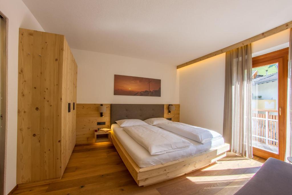 a bedroom with a large bed and a large window at Appartement Hotel Erlhof Deluxe in Lutago