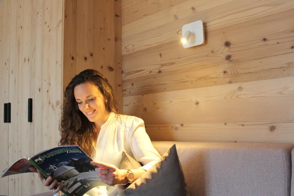 a woman is reading a magazine in a room at Appartement Hotel Erlhof Deluxe in Lutago
