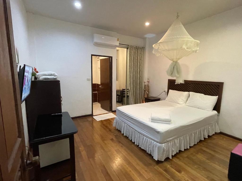 1 dormitorio con cama blanca y lámpara de araña en Nawaporn Place, en Phuket