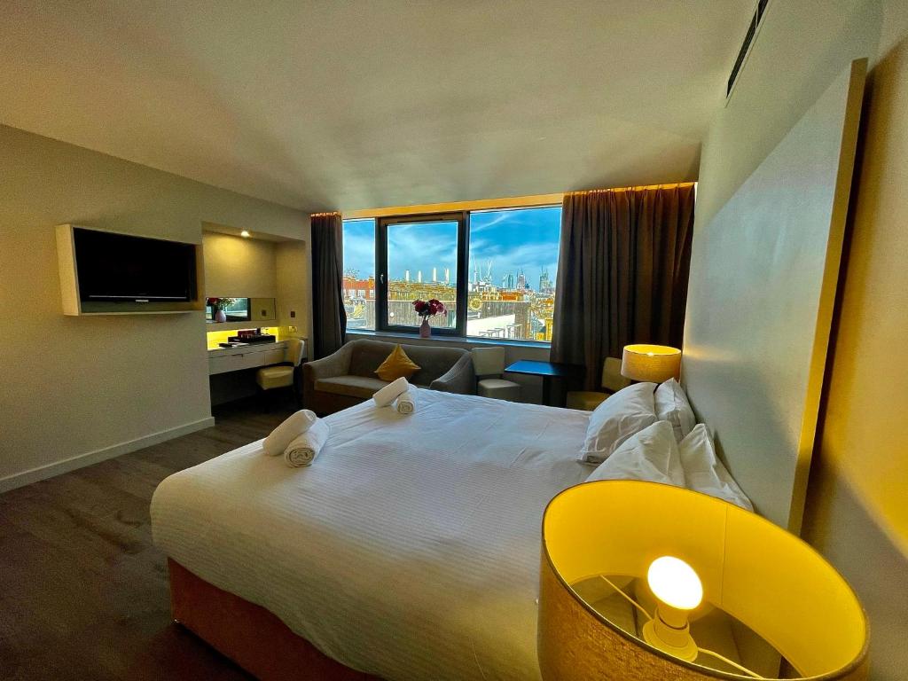 ロンドンにあるAxiom Park Hotelの大きなベッドと大きな窓が備わるホテルルームです。