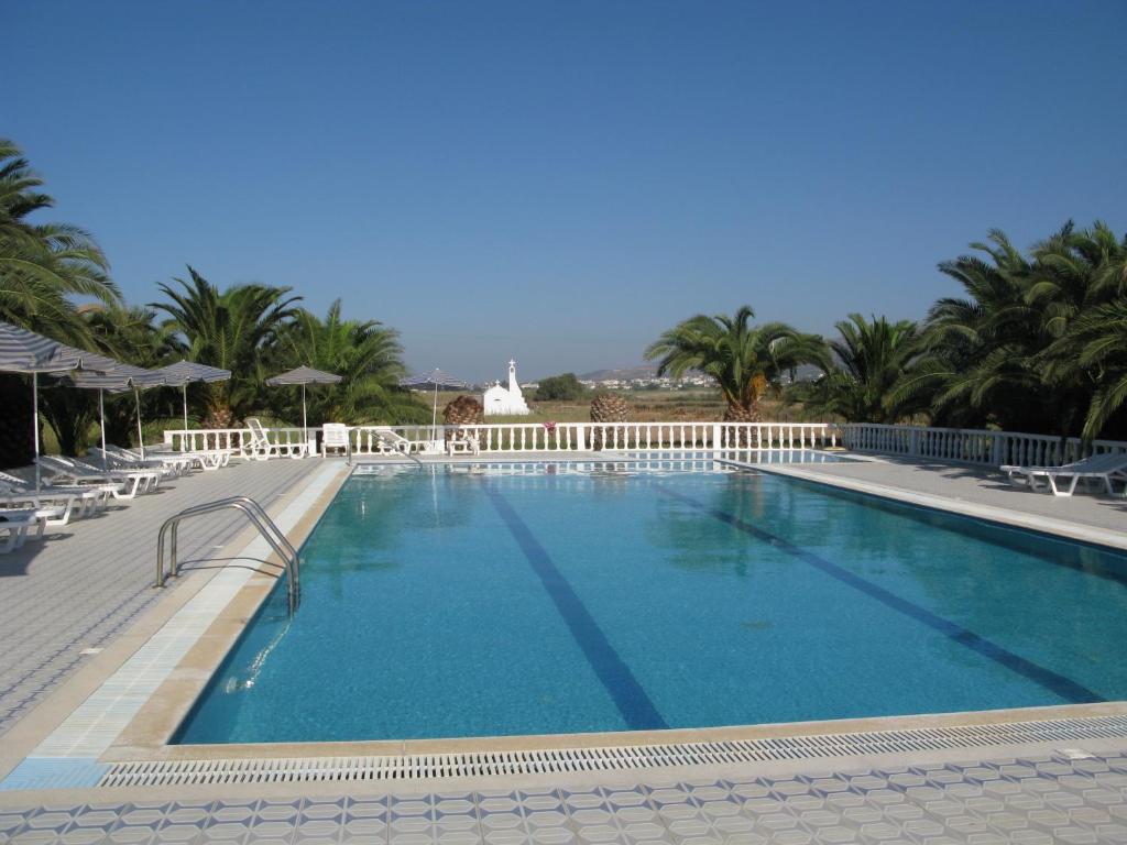 a large swimming pool with chairs and palm trees at Mariliza Beach Hotel in Marmari