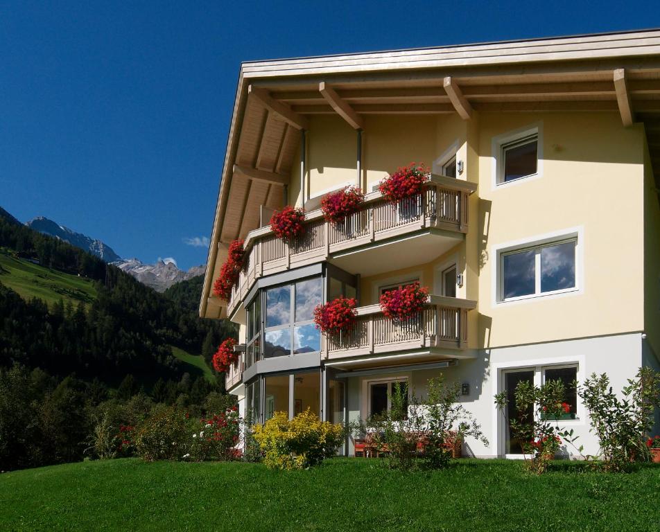 a building with red flowers on the balconies at Appartement Hotel Erlhof Deluxe in Lutago