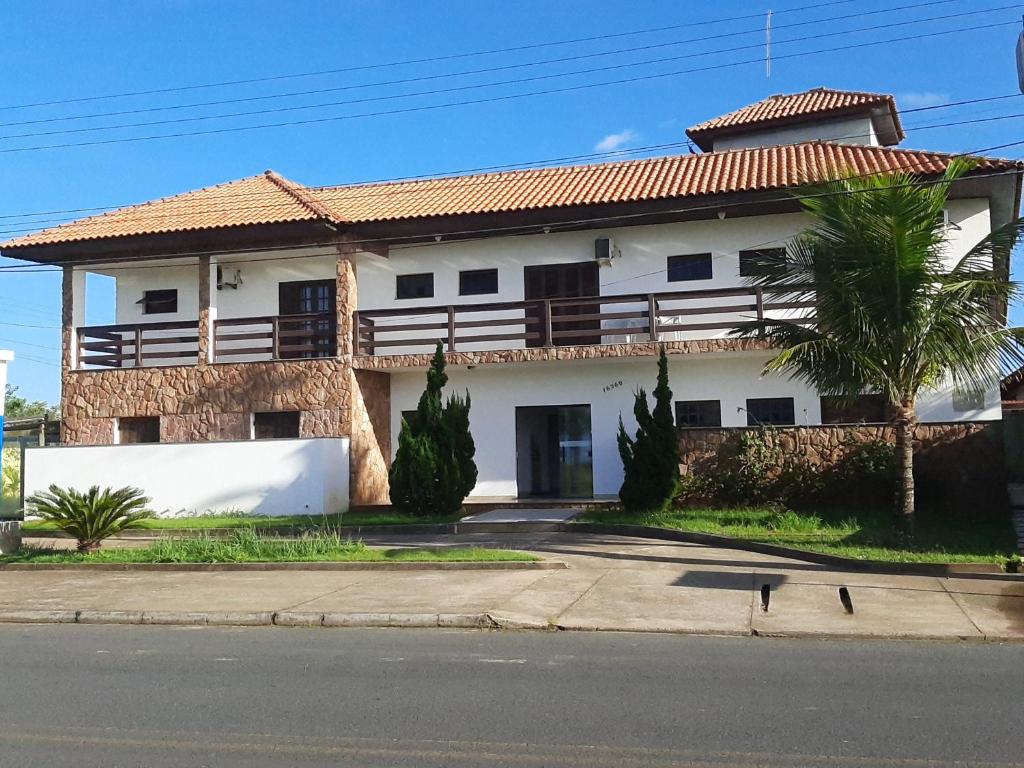 una casa blanca con una palmera delante de ella en Toya Hotel, en Ilha Comprida