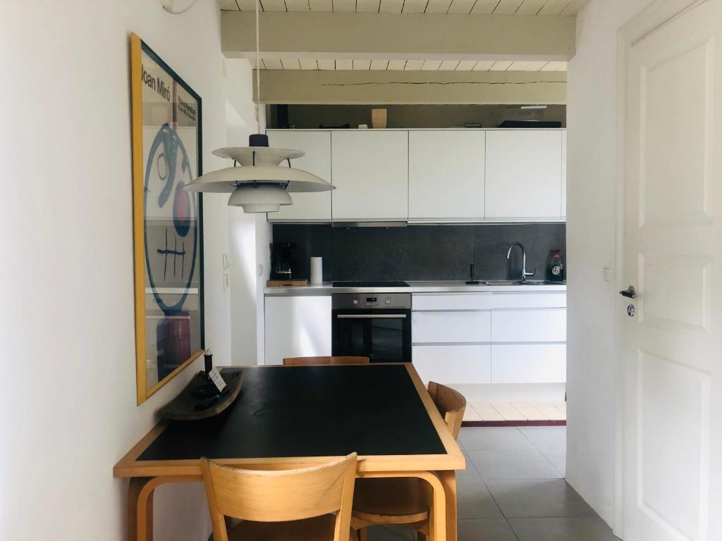 uma cozinha com uma mesa preta e algumas cadeiras em Gladeholm em Kivik