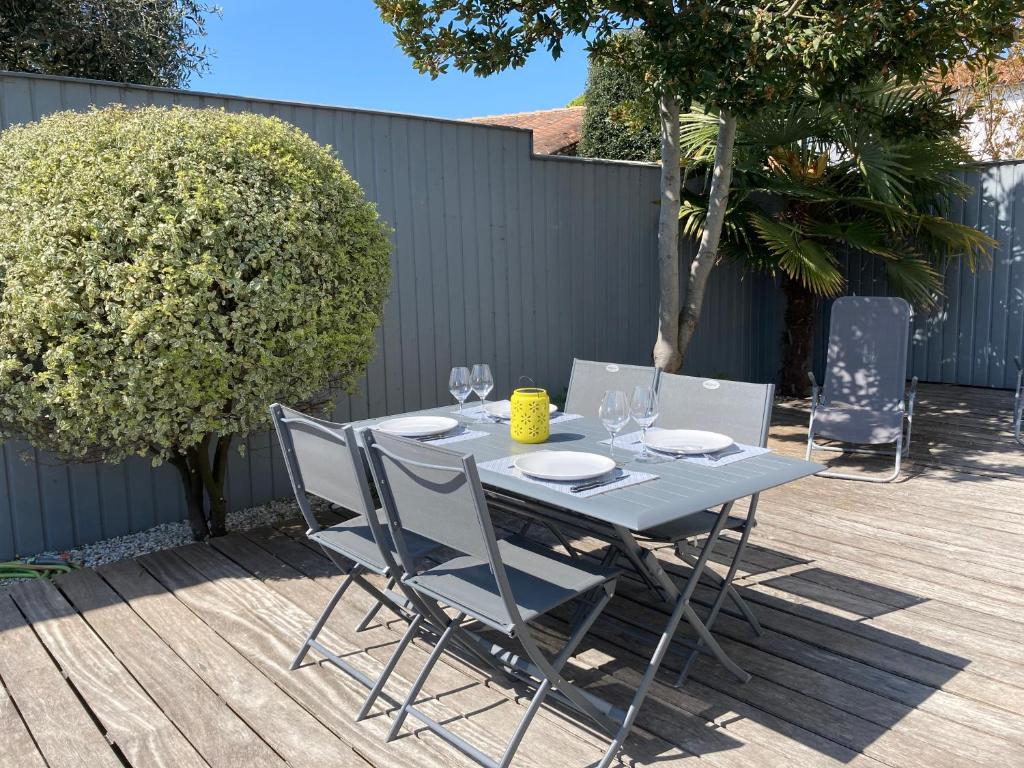 - une table avec des chaises et des verres à vin sur la terrasse dans l'établissement Jolie location contemporaine dans Saint Martin de Ré, à Saint-Martin-de-Ré