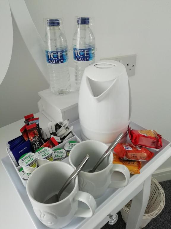 un estante en una nevera con dos tazas y botellas de agua en The Antelope Hotel, en Merthyr Tydfil