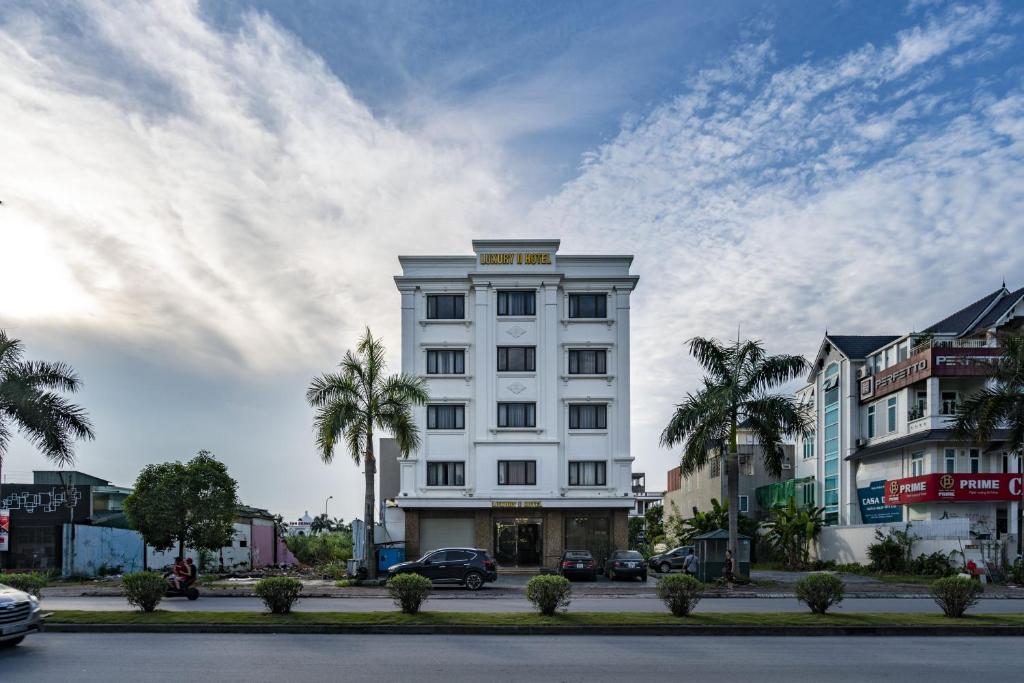 un edificio blanco con palmeras delante en LUXURY II HOTEL, en Ha Long