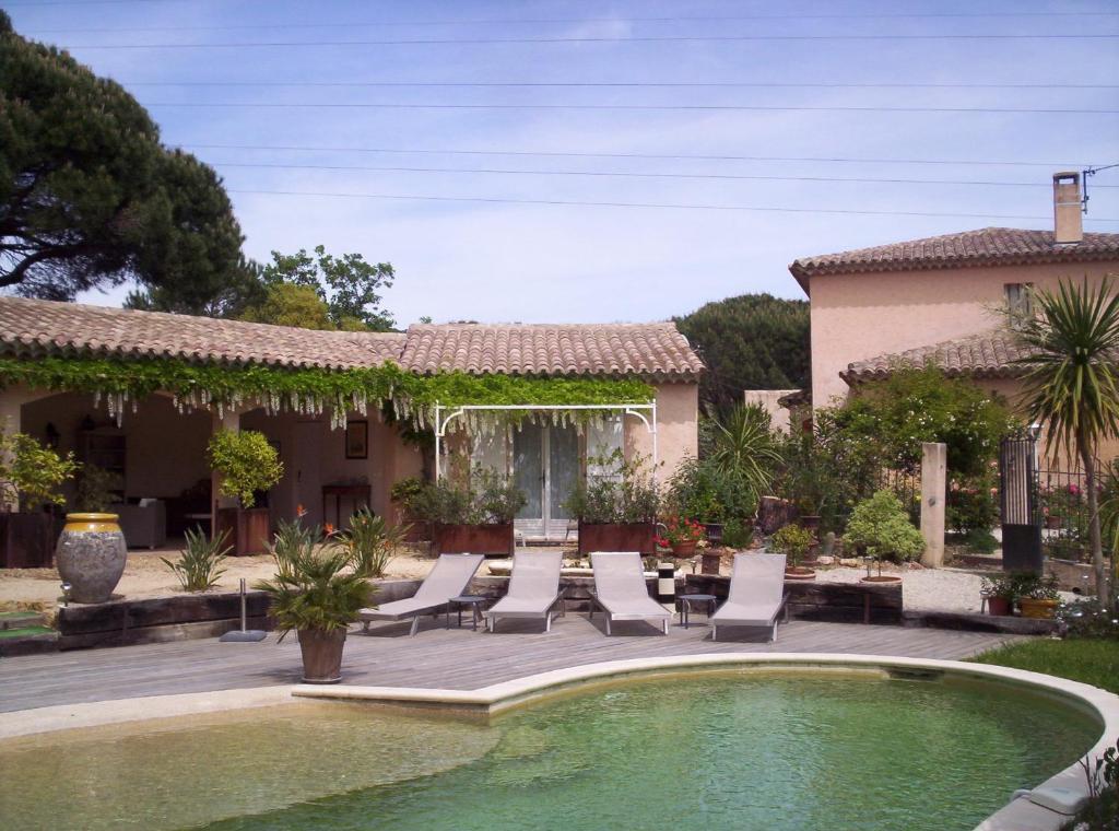 een huis met een zwembad met stoelen en een patio bij Les Glycines in Grimaud
