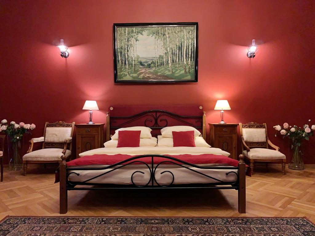 a bedroom with a bed with red walls and two chairs at Small Luxury Palace Residence in Prague