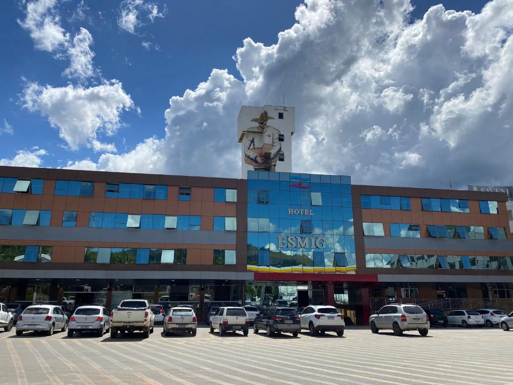 a building with cars parked in a parking lot at Hotel Esmig in Venda Nova do Imigrante