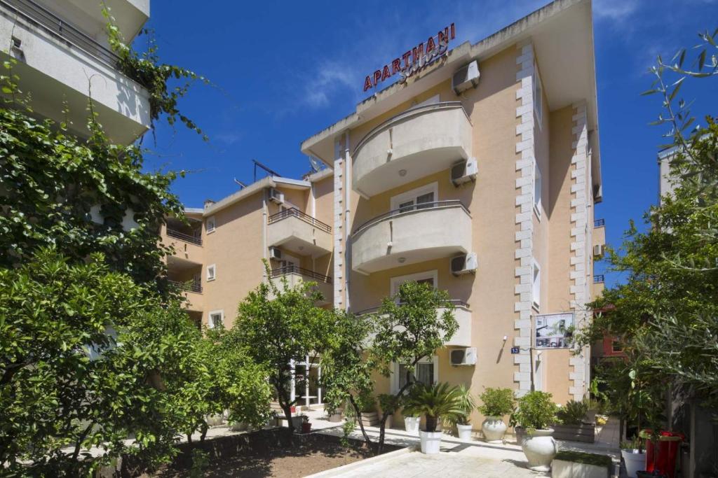 a tall building with trees in front of it at Apartmani Salus in Budva