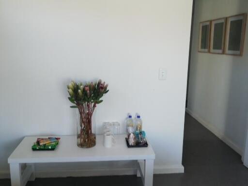 a white table with a vase of flowers on it at Knysna Budget Friendly Stay in Knysna